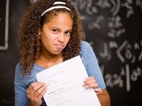 Unhappy girl holding up a paper marked with a C, an average grade.