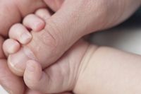 Photo of a baby's hand grabbing father's thumb.