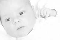 Black and white photo of a baby, alone, looking off in the distance