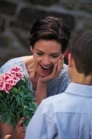 Photo of a boy giving flowers to his mother