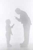 Silhouette of father disciplining his son with a scolding