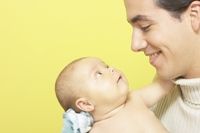 Father holding baby, smiling and looking into each other's eyes