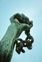 Freedom illustrated with photo of a statue, with a hand holding a broken chain