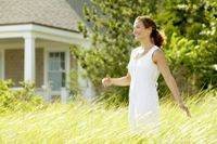 Happy woman walking through field of tall grass.