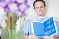 Photo of a man in the hospital cheered by reading a get well card.