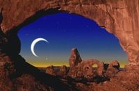 The moon and stars seen through a natural rock archway.