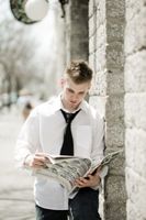 Young man reading tabloid newspaper