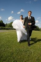 Bride girding up her wedding dress running with groom.