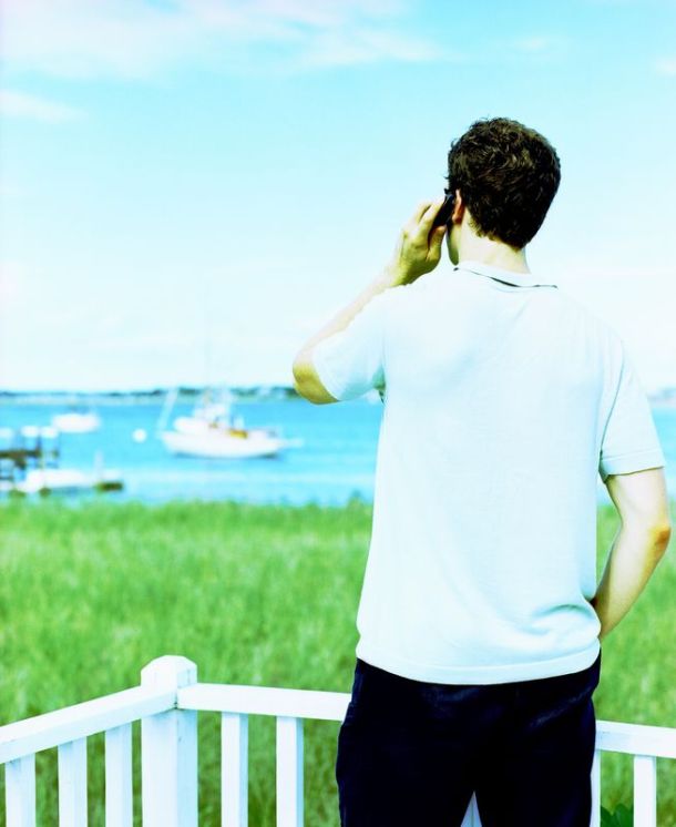 Photo of a young man making a phone call overlooking a harbor