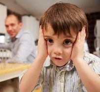 Photo of a reluctant son with hands on his face and his father looking over his shoulder