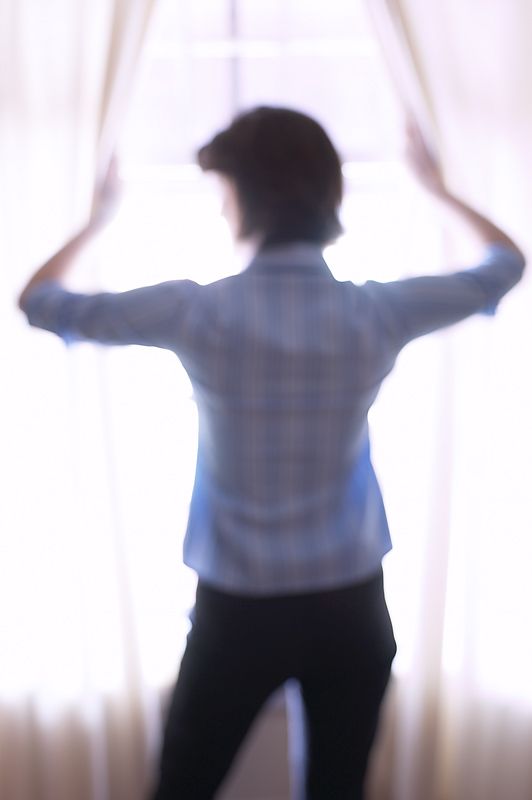 Woman looking comtemplatively through window, looking back